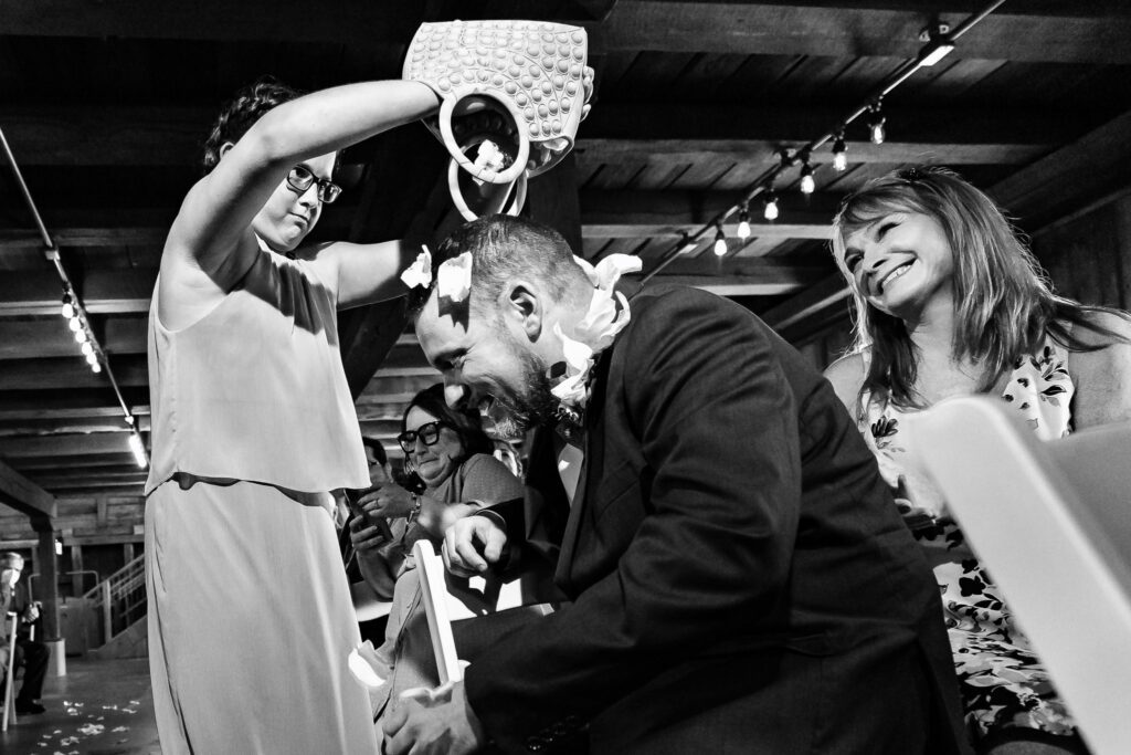 A young girl pours flower petals on the groom in a unique twist on a petal toss.