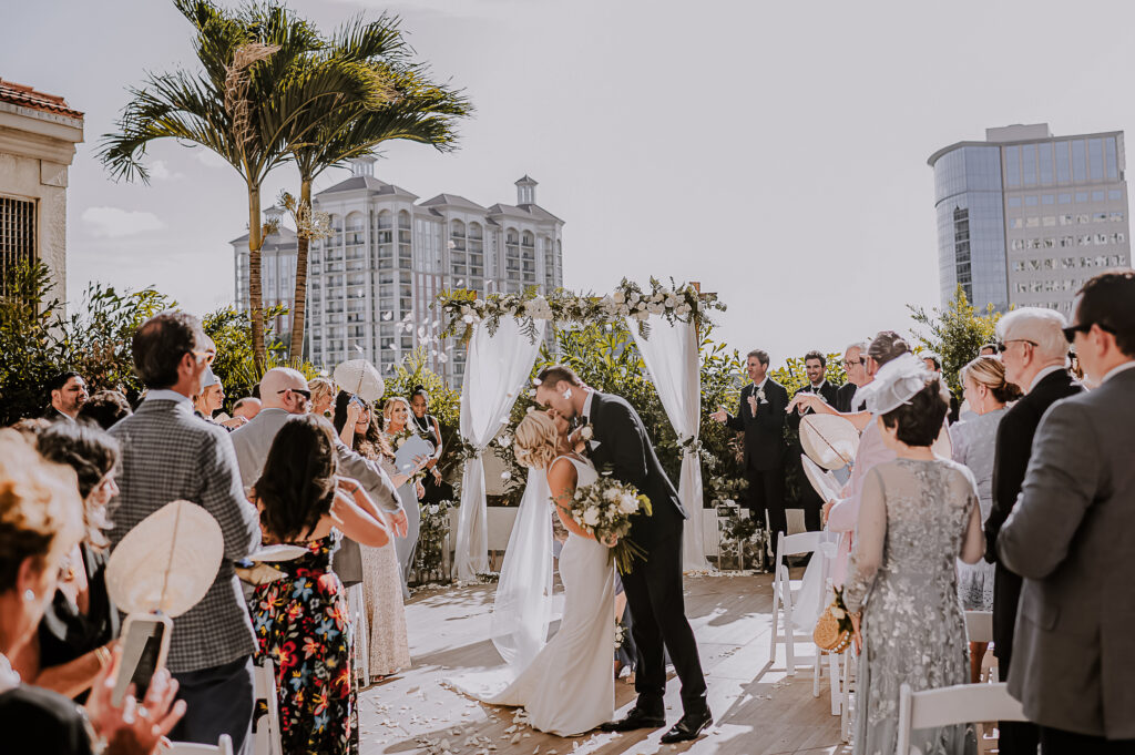 Newlyweds have their "first kiss" during a petal toss at their wedding.