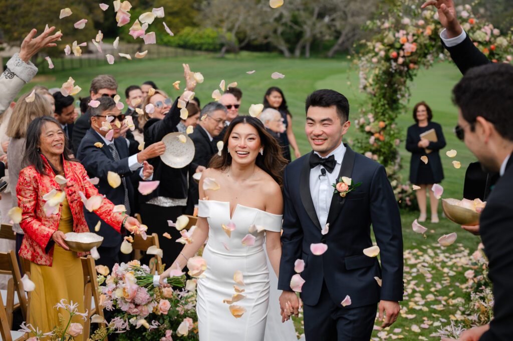 Newlyweds walk down the aisle during a petal toss recessional.