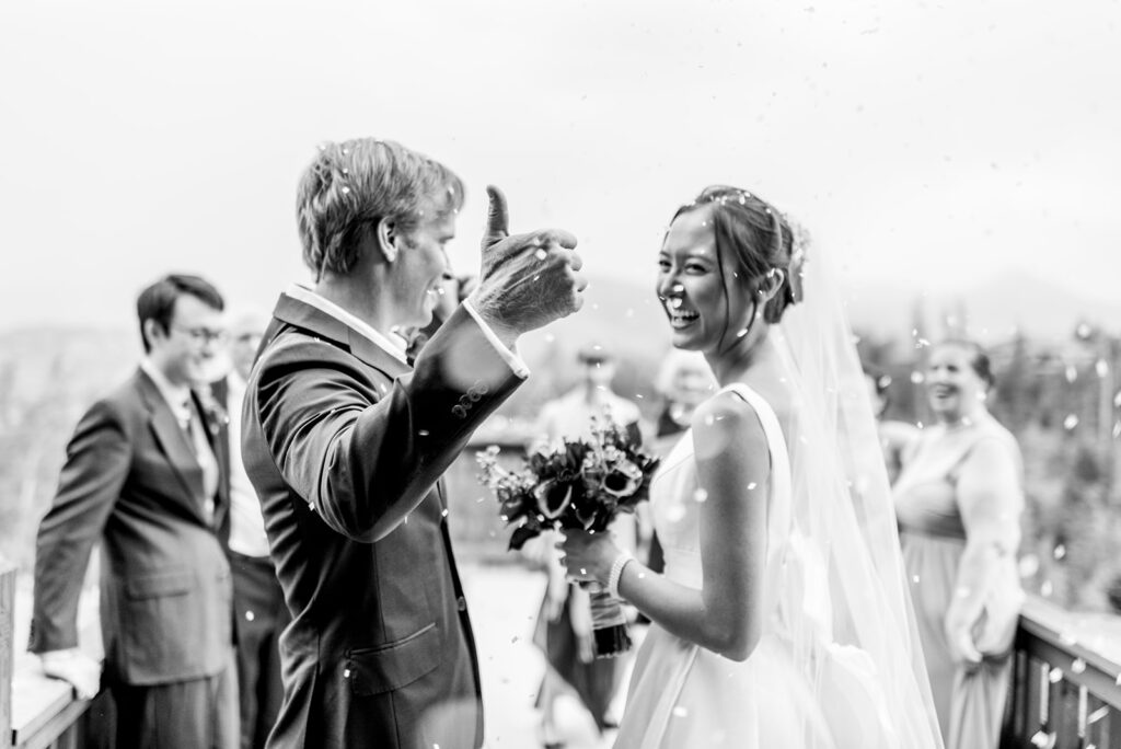 The groom gives a thumbs up during a petal toss featuring rice. 