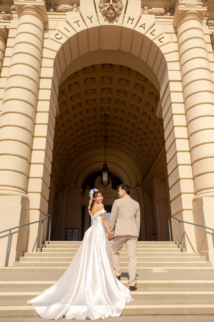 Couple climbing city hall steps with a long train spilling down behind them